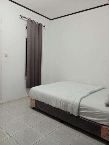 a bed in a white room with a bed frame at RedDoorz @ Pantai Sayangheulang in Cilauteureun