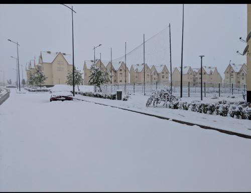 a snow covered parking lot with houses and a fence at Appartement Au jardin in Ifrane
