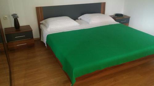 1 dormitorio con 1 cama con manta verde en Antunes Apartment en Jarebinjak