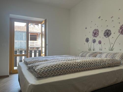 1 dormitorio con 1 cama con flores en la pared en Borgo Bliss Apartment, en Tenno