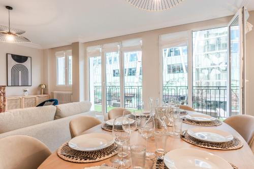 une salle à manger avec une table, des chaises et des fenêtres dans l'établissement Fantastic Family Apartment - 20min from city center, au Kremlin-Bicêtre