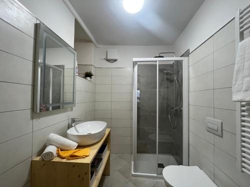 a white bathroom with a sink and a shower at Borgo Bliss Apartment in Tenno