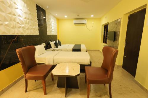 ein Hotelzimmer mit zwei Betten und einem Tisch und Stühlen in der Unterkunft Kailasaa Residency in Tiruvannāmalai