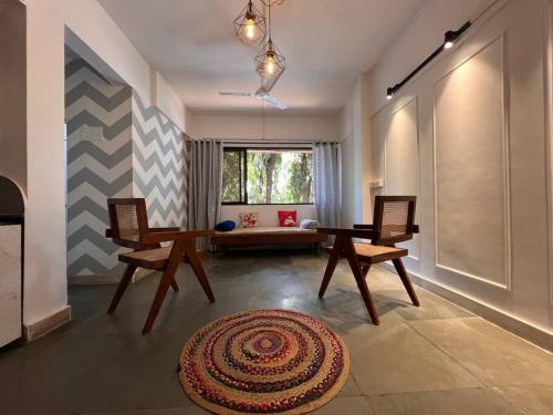 a living room with two chairs and a table and a rug at Home Stay in Mumbai