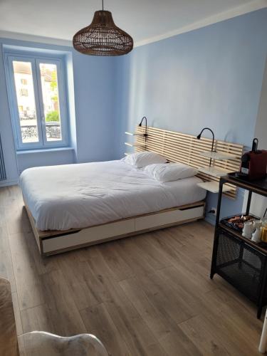 a bedroom with a large bed with a wooden headboard at Chambres d'hôtes du Bistrot d'ici in Saint-Saturnin