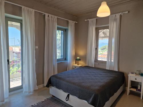 een slaapkamer met een bed en 2 ramen bij Filia Country House in Fília