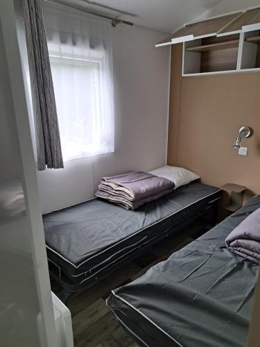 a small room with two beds and a window at Camping du Domaine de la Forge in La Teste-de-Buch