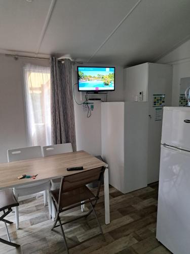 a kitchen with a table and a television on the wall at Camping du Domaine de la Forge in La Teste-de-Buch