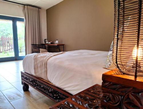 a bedroom with a bed with a table and a window at Tala Collection Game Reserve in Silverton