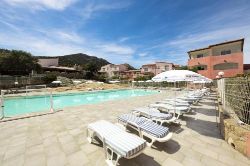 a swimming pool with lounge chairs and an umbrella at Ferienhotel Maristella in Algajola