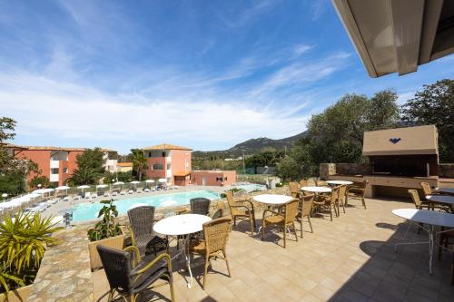 un patio con mesas y sillas junto a una piscina en Ferienhotel Maristella, en Algajola