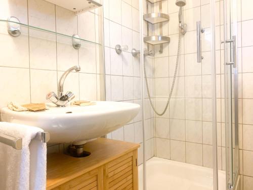 een witte badkamer met een wastafel en een douche bij Hübsches Cottage in ehemaliger Gärtnerei in Meerbusch