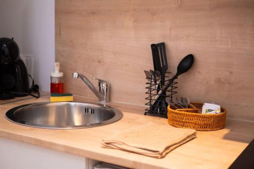 - un comptoir de cuisine avec évier et ustensiles en acier inoxydable dans l'établissement Studio Paisible 2pers wifi gare, à Saint-Quentin