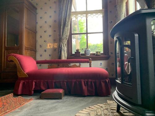 a living room with a red couch and a window at De Middelste Dam in Mildam