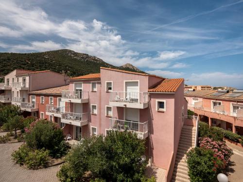 a row of apartment buildings with balconies and a mountain at Ferienhotel Maristella in Algajola