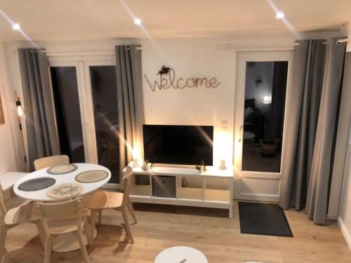 un salon avec une télévision, une table et des chaises dans l'établissement Maisonnette La petite Jeanne, à Boves