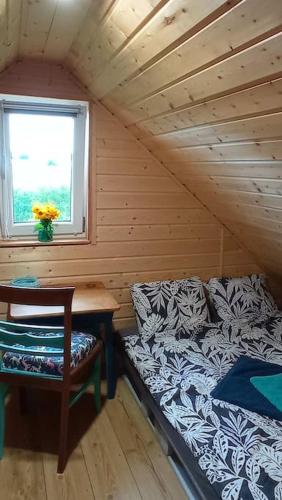 a bed and a table in a room with a window at Uroczy domek na Mazurach in Nowe Kiejkuty