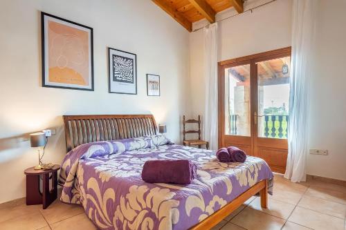 a bedroom with a bed with purple sheets and a window at Maravillosa finca con piscina in Marratxi