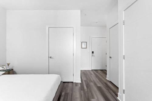 a white bedroom with white walls and wooden floors at Mid-Century Modern Studio CozySuites Downtown in Indianapolis