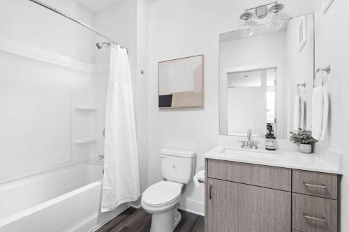 a white bathroom with a toilet and a sink at Mid-Century Modern Studio CozySuites Downtown in Indianapolis