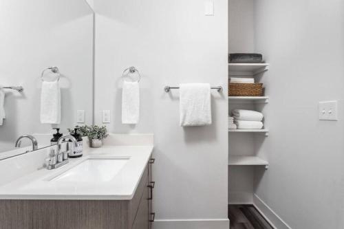 een witte badkamer met een wastafel en een spiegel bij Dream Apartment near Whole Foods CozySuites in Indianapolis