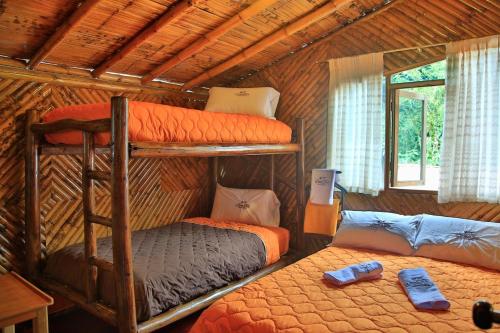 a bedroom with two bunk beds in a log cabin at La Posada de Mindo in Mindo