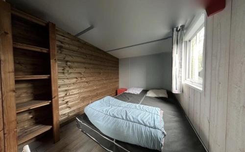 a bedroom with a bed and a wooden wall at Mobilhome tout confort in La Teste-de-Buch