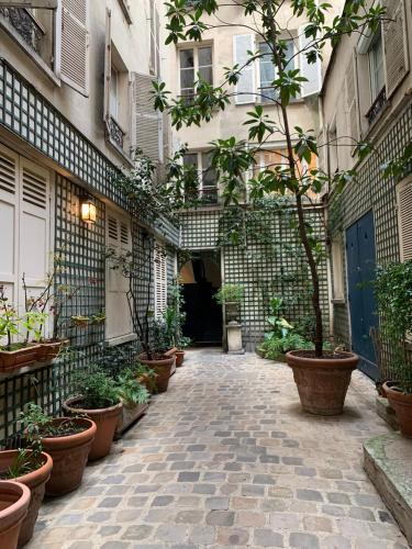 une cour avec des plantes en pot sur le côté d'un bâtiment dans l'établissement Mignonne, à Paris
