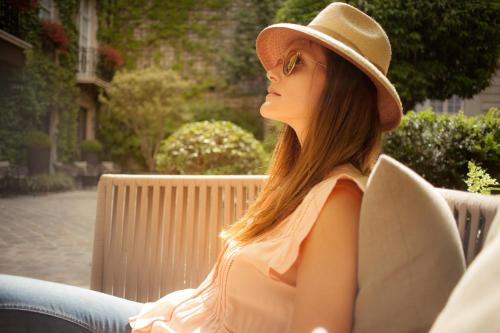 a woman wearing a hat sitting on a bench at Le Pavillon de la Reine & Spa - Small Luxury Hotels of the World in Paris