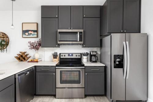 a kitchen with black cabinets and a stainless steel refrigerator at CozySuites Modern Studio steps from Broad Ripple in Indianapolis