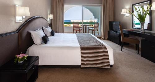 um quarto de hotel com uma cama grande e uma secretária em El Mouradi Palace em Port El Kantaoui