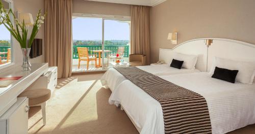 um quarto de hotel com uma cama grande e uma varanda em El Mouradi Palace em Port El Kantaoui