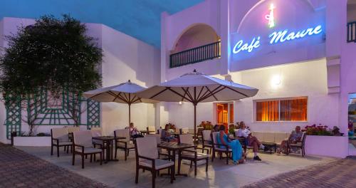 a group of people sitting at tables in front of a restaurant at El Mouradi Palace- Couple et Famille uniquement in Port El Kantaoui