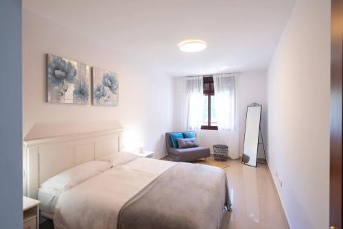 a white bedroom with a bed and a chair at Phoebe Apartment - city centre of Santa Cruz in Santa Cruz de la Palma