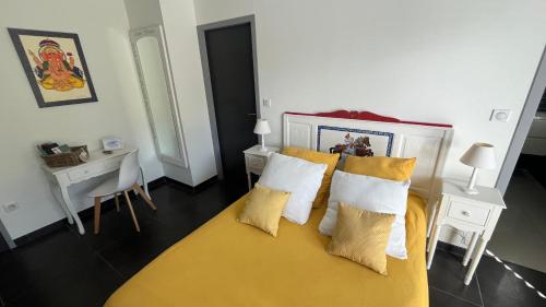 a bedroom with a yellow bed with pillows and a desk at Domaine Georges V in Saint-Junien