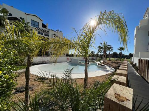 een zwembad met palmbomen voor een gebouw bij TODIMER Apartamento lujo in Motril