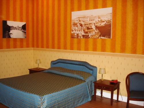 um quarto com uma cama azul com duas mesas e duas fotografias em Hotel Excelsior em Cosenza