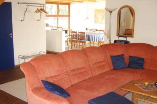 an orange couch with blue pillows in a living room at Deetje in Borkum
