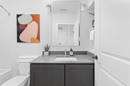a bathroom with a sink and a toilet and a mirror at Spacious 2BR in Meridian Kessler by CozySuites in Indianapolis