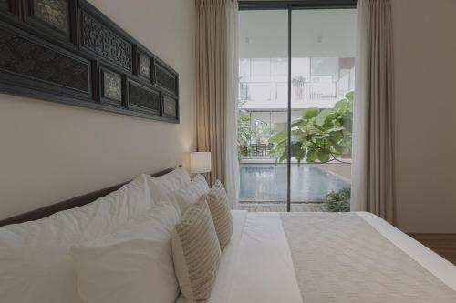 a bedroom with a white bed with a large window at Nhãn Stay in Hue