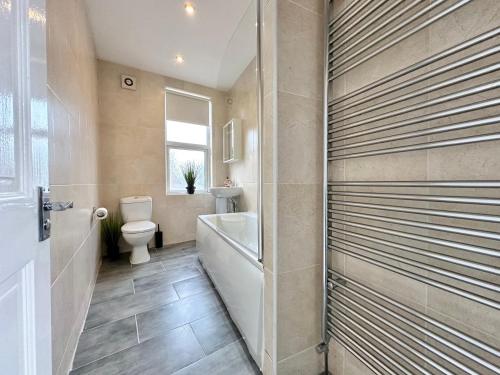 a bathroom with a toilet and a tub and a sink at Large 4 Bedroom Home, Close To Leeds City Centre in Kirkstall