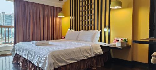 ein Schlafzimmer mit einem großen Bett mit gelben Wänden und einem Fenster in der Unterkunft Sunway Resort Suites@Sunway Pyramid and Sunway Lagoon in Kampong Penaga