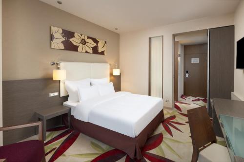 a bedroom with a large white bed and a desk at Golden Tulip Ana Dome Hotel in Cluj-Napoca