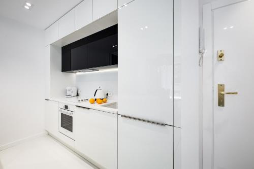 a kitchen with white cabinets and a tv at Dune Beach Resort in Mielno