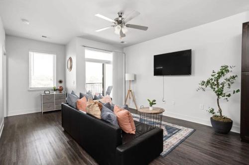 a living room with a black couch and a ceiling fan at Cozysuites Spacious 2BR next to Whole Foods in Indianapolis