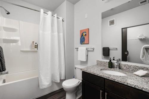 a white bathroom with a toilet and a sink at Cozysuites Spacious 2BR next to Whole Foods in Indianapolis