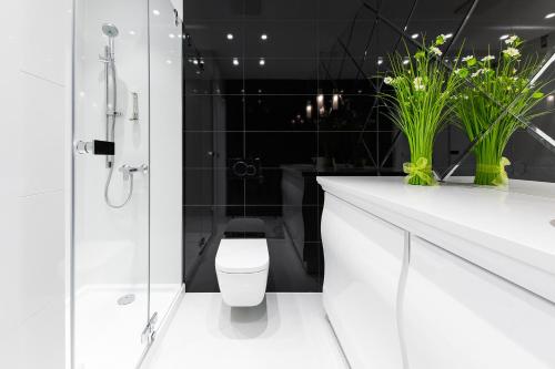 a white bathroom with a toilet and a shower at Dune Beach Resort in Mielno