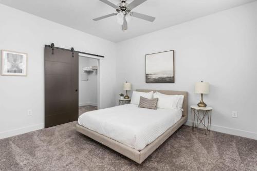 a white bedroom with a bed and a ceiling fan at CozySuites 2BR - Nora, Indianapolis in Indianapolis