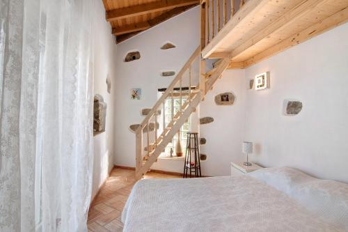 a bedroom with a white bed and a staircase at Casa da Maria Teresa in Santa Catarina da Fonte do Bispo