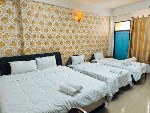 - une chambre avec 2 lits avec des draps blancs et un mur dans l'établissement SB Betong ห้องพักรายวัน, à Betong